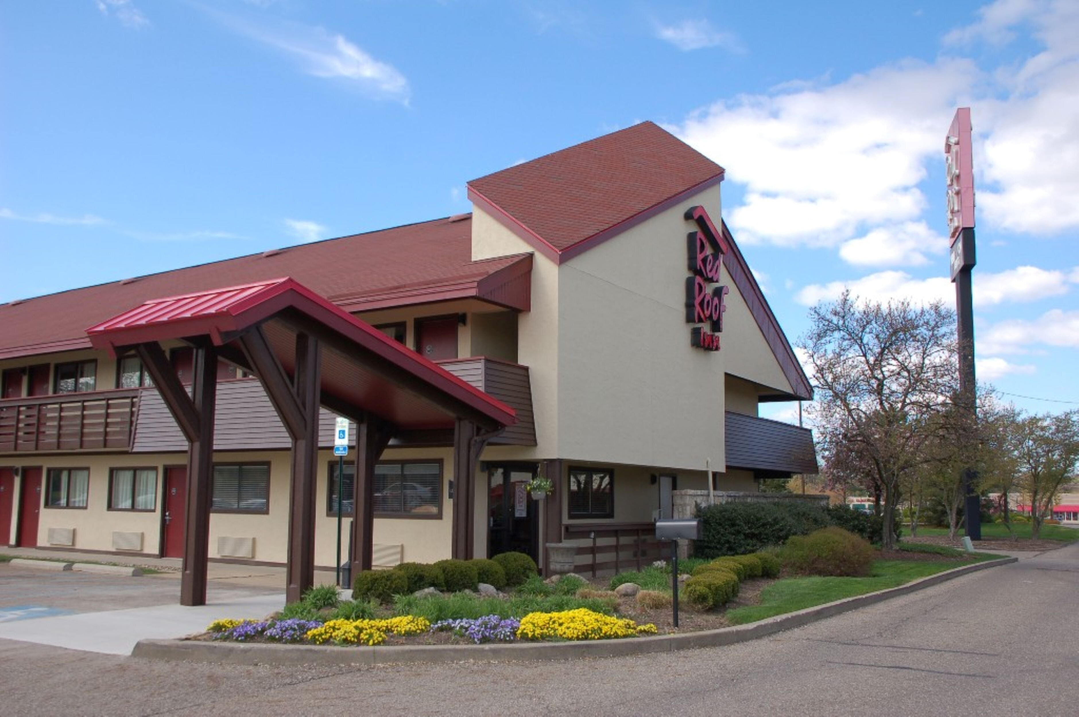 A motel with a red roof, a covered entrance, and a sign that reads 'Red Roof Inn'.