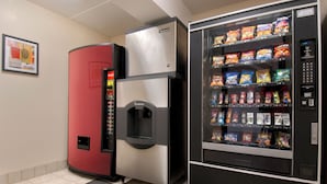 A vending machine stocked with snacks and a red refrigerator. - Red Roof Inn Canton (North Canton)