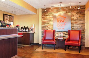 Zona de recepción de Red Roof Inn con pared de ladrillo, mostrador con máquina de café y dos sillones de cuero.