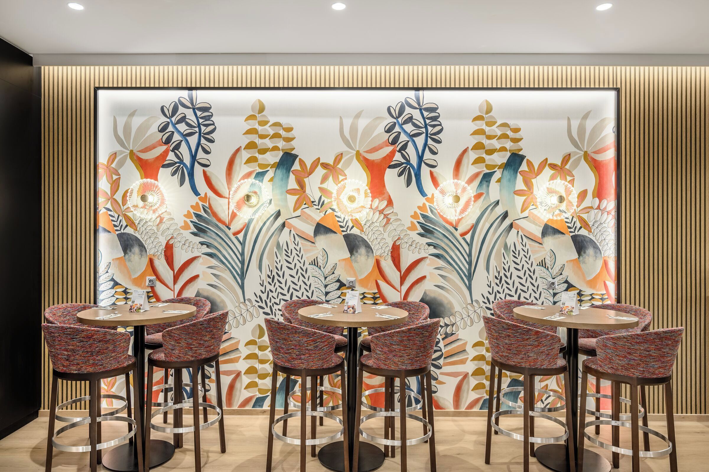 Un comedor con una mesa redonda y cuatro sillas, una pared decorativa con estampado floral y un diseño de paneles de madera.
