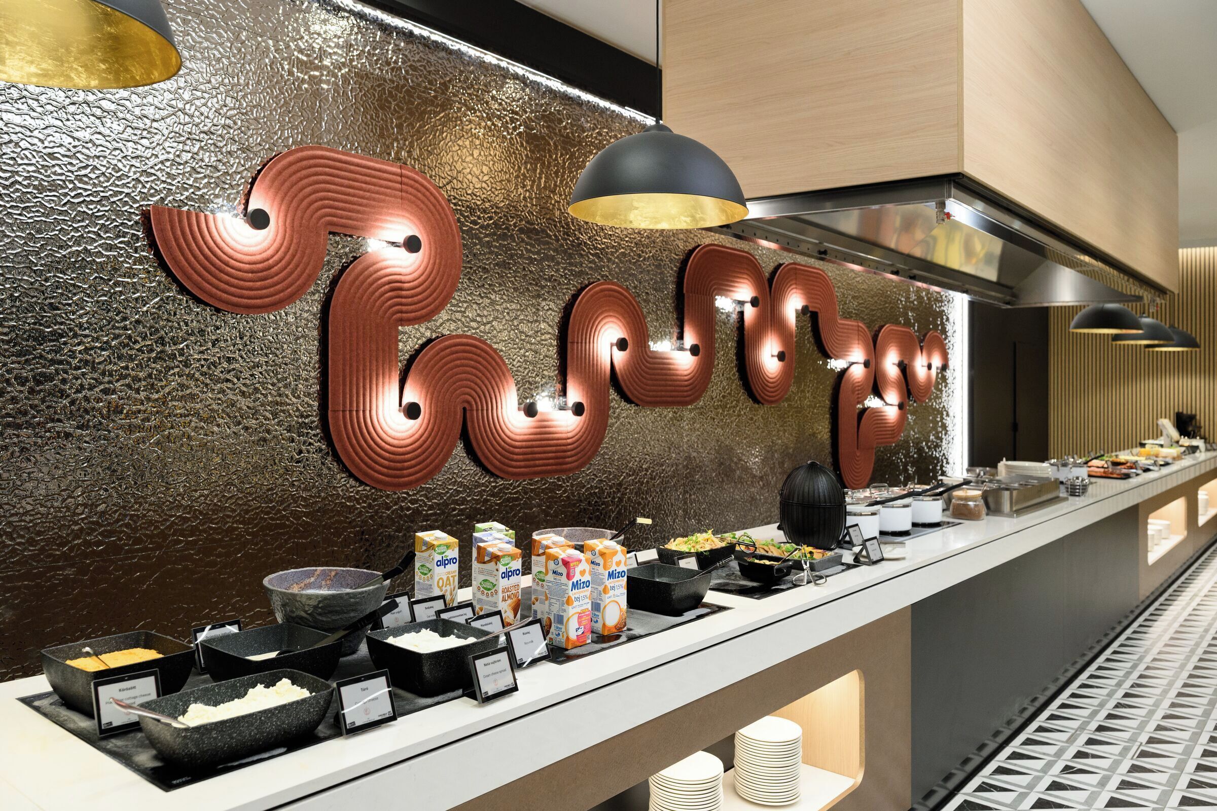 Un bufé de desayuno con diferentes alimentos y una pared con letras iluminadas.