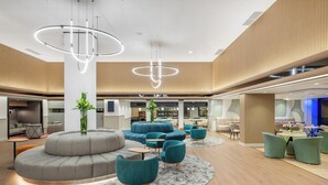 Un hall d’entrée moderne doté d’un espace salon circulaire, de lambris en bois et d’une plante au centre.