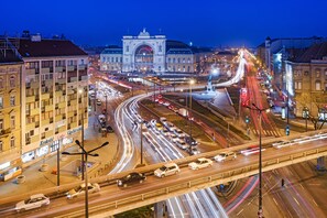 Egy forgalmas, központi elhelyezkedésű kereszteződés, ahol több útszakasz találkozik, és a háttérben egy feltűnő, klasszikus stílusú épület emelkedik.