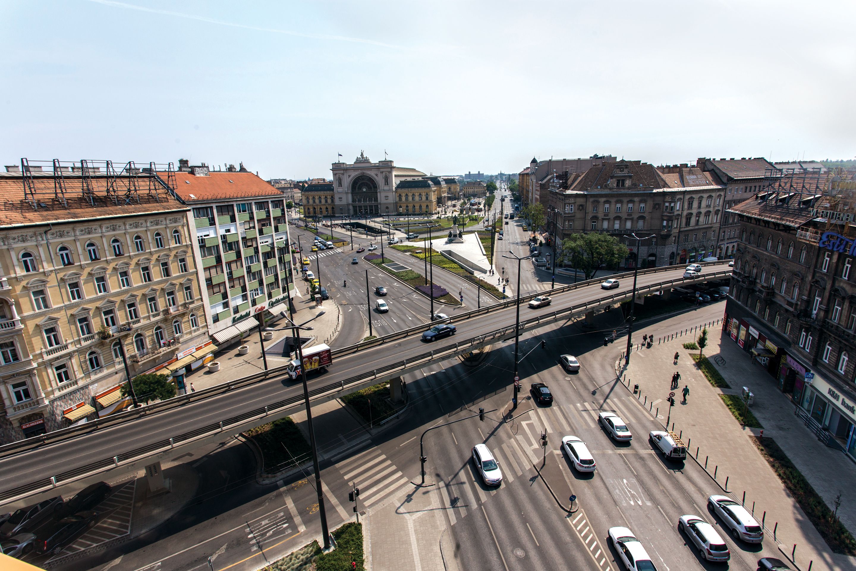 A multi-level urban intersection with buildings, a pedestrian walkway, and a bridge.