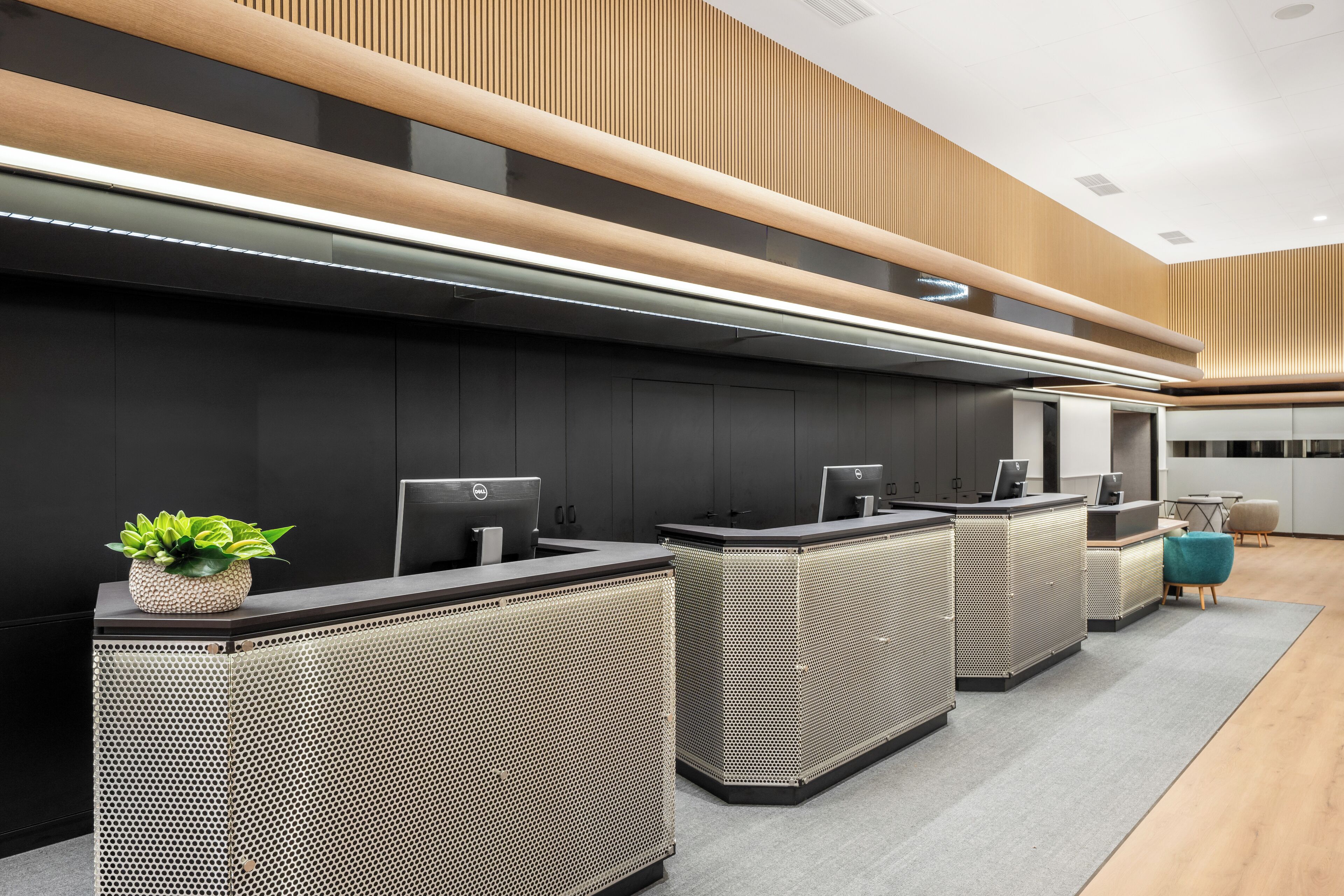 Zona de recepción con diseño moderno, que incluye un mostrador de recepción, estaciones de computadoras y una planta en maceta.