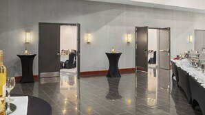 A modern hotel lobby with a polished tile floor, black round tables, and a buffet area with a long counter.