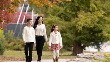 A family walking on a path in a park with trees and a distant building.