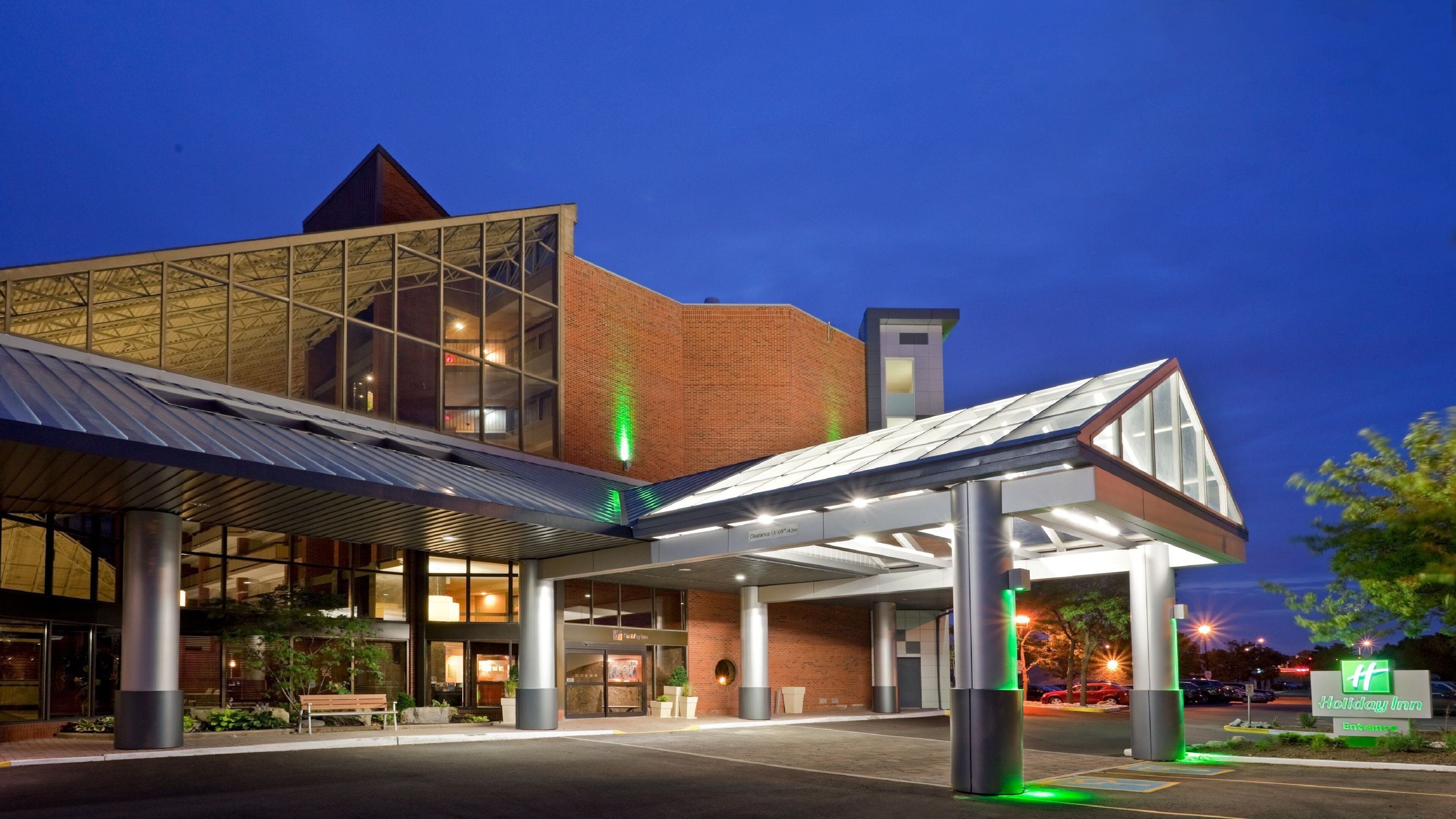 Un hôtel Holiday Inn doté d’une architecture moderne, caractérisé par une grande façade en verre et un espace d’entrée abrité.