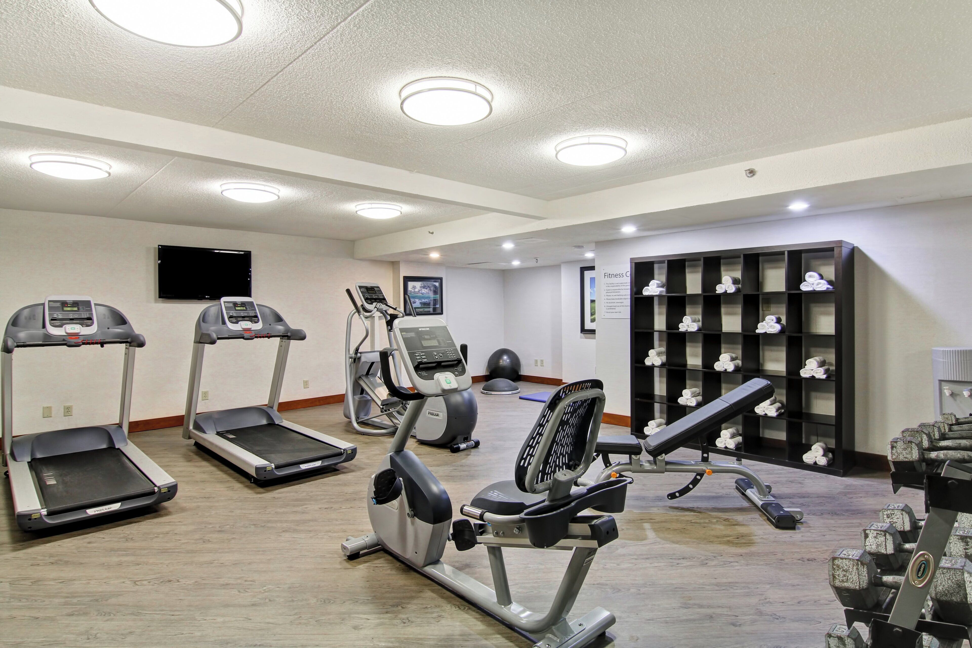 A gym with treadmills, an elliptical, a stationary bike, and weightlifting equipment.
