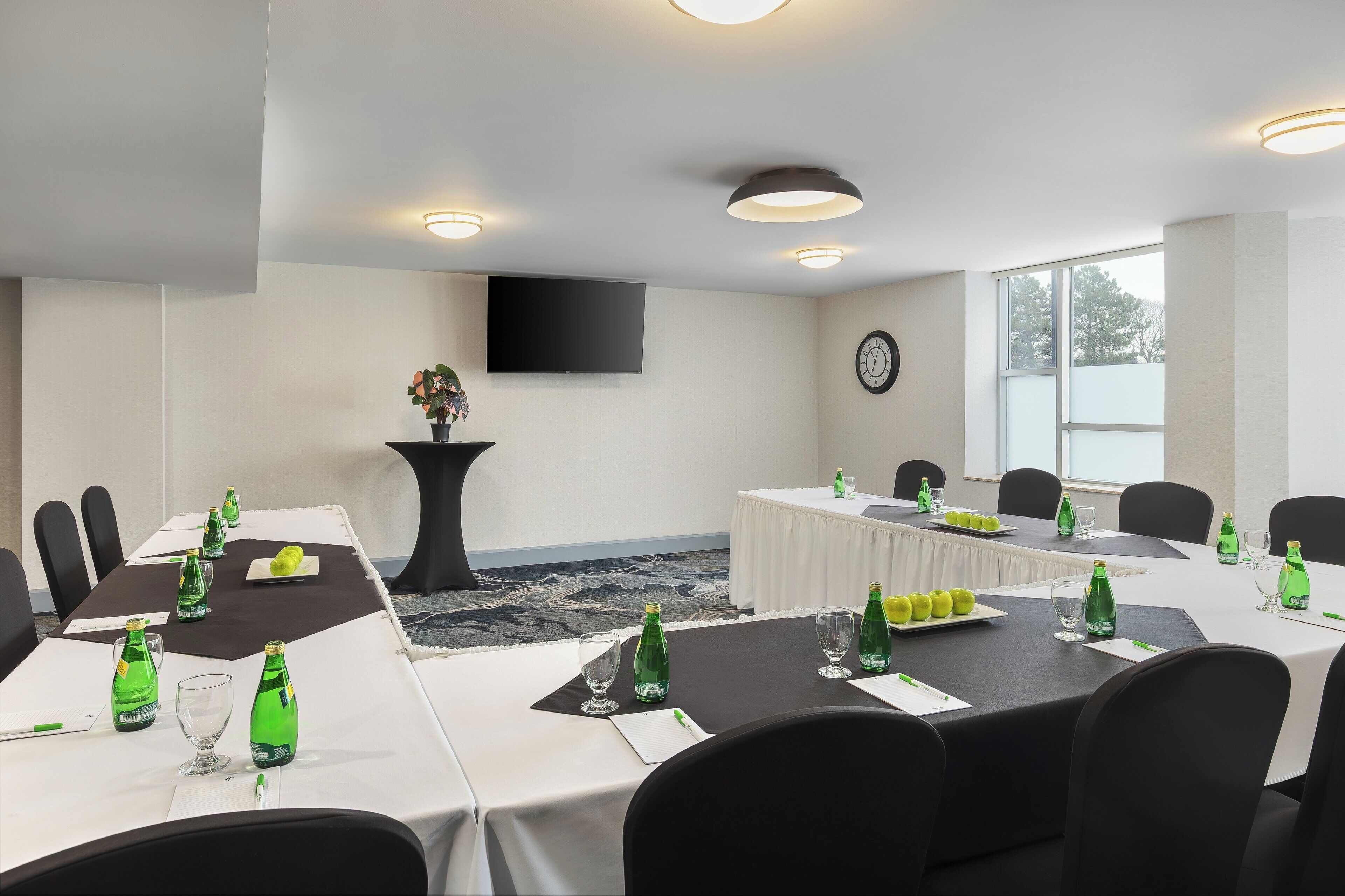 A conference room with tables set for a meeting, equipped with chairs, tables, and glassware.
