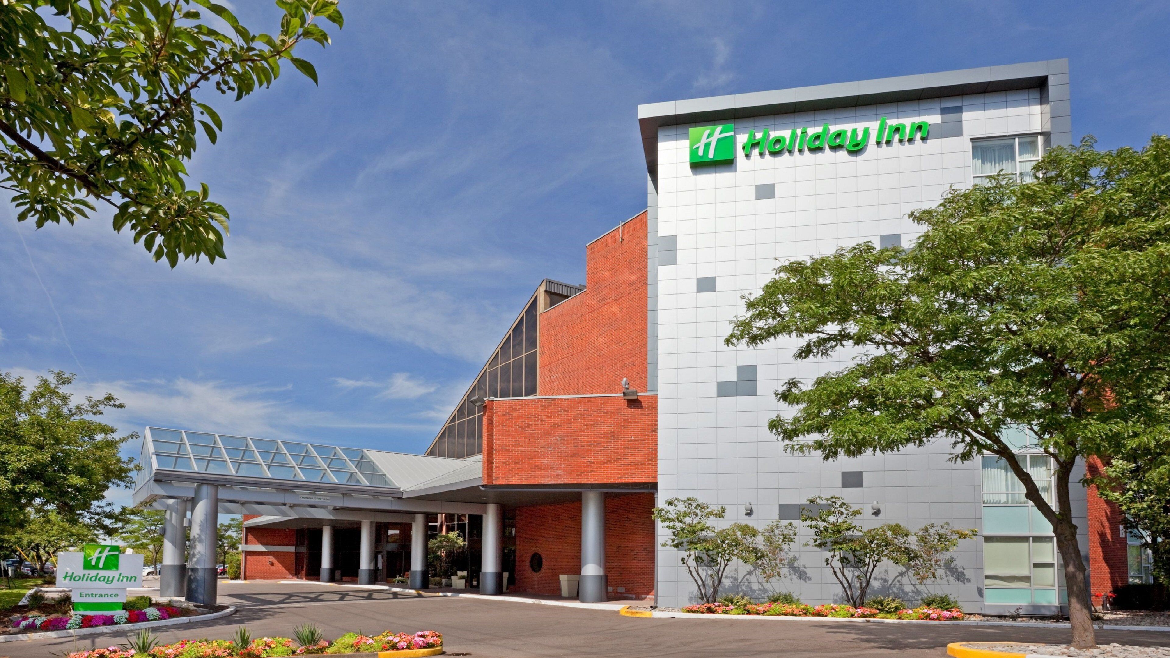 Un hôtel Holiday Inn au design moderne, avec une entrée imposante et une vue dégagée sur le ciel.