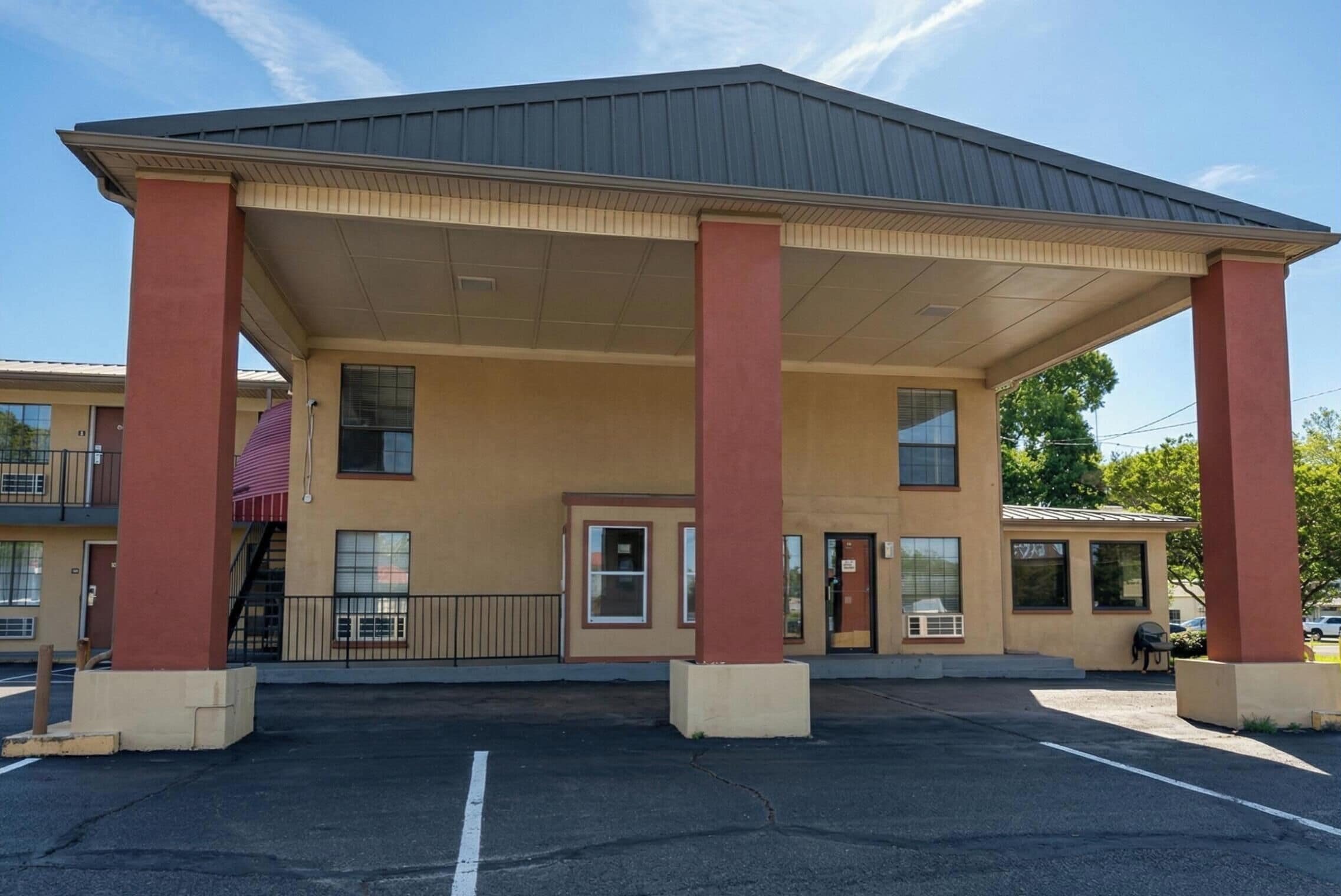 A building with a covered entrance, columns, and a parking lot.