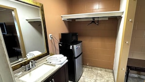 A bathroom with a sink, mirror, black microwave, and a small refrigerator. - Diamond Inn Forrest City I-40 (Forrest City)