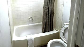 Un baño pequeño con bañera, inodoro y cortina de ducha.