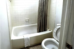 Un baño pequeño con bañera, inodoro y cortina de ducha.