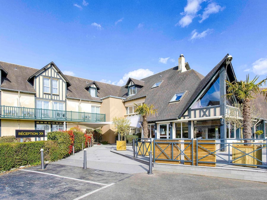A hotel with a reception area, multiple buildings with varying roof designs, and a gated entrance.