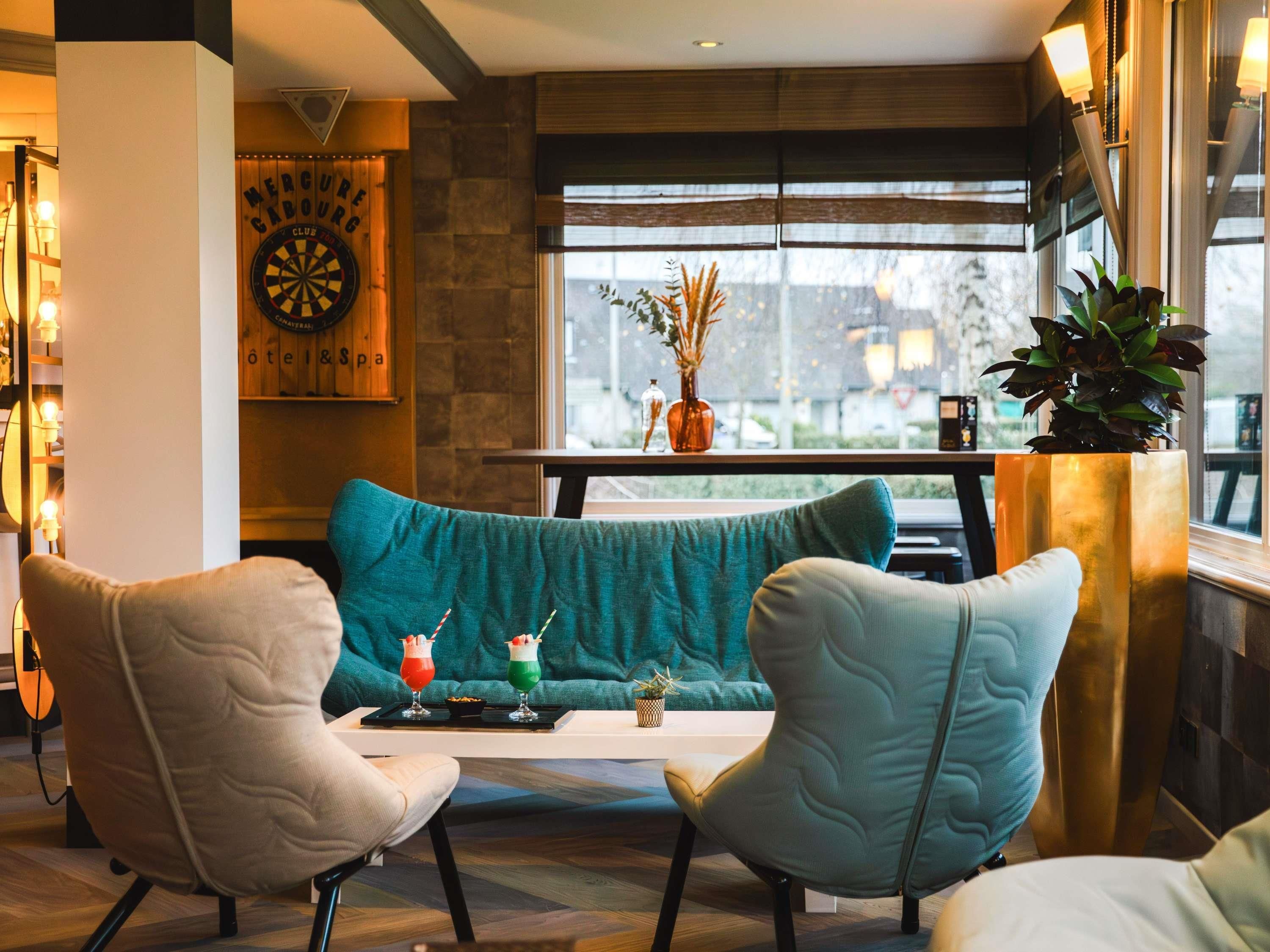 A cozy seating area with teal cushions, a dartboard, and a window with a view of the city.