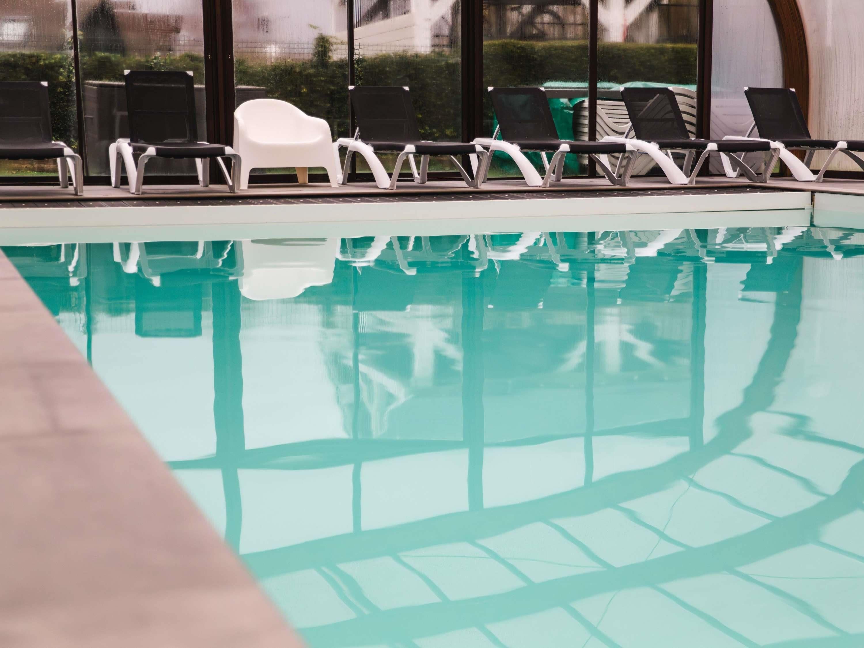 A swimming pool with lounge chairs and a white chair.
