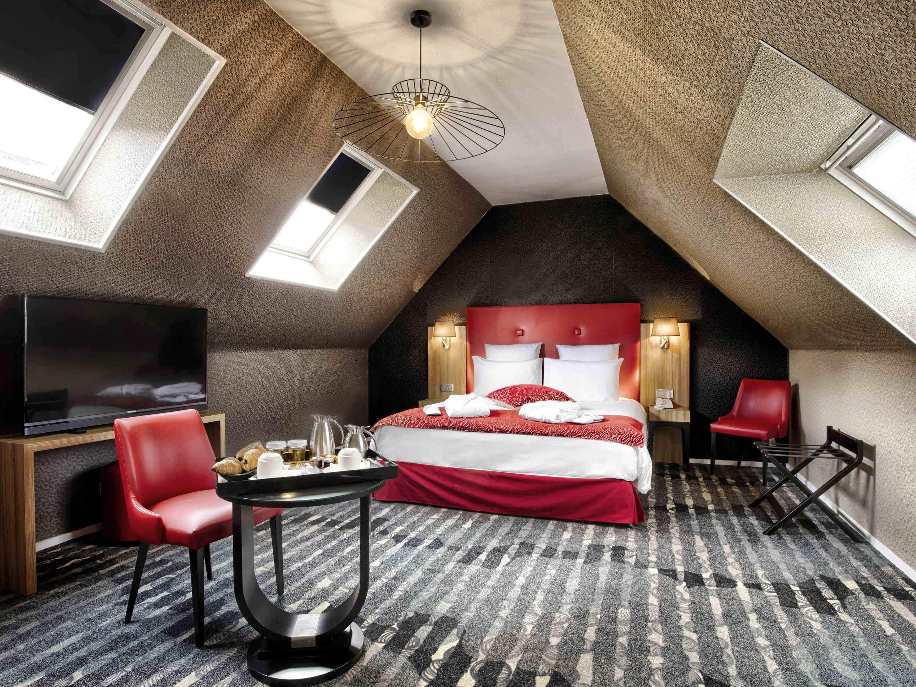 Ein Hotelzimmer mit einem großen Bett, einem Fernseher, einem Schreibtisch mit Stuhl und einem kleinen Tisch.