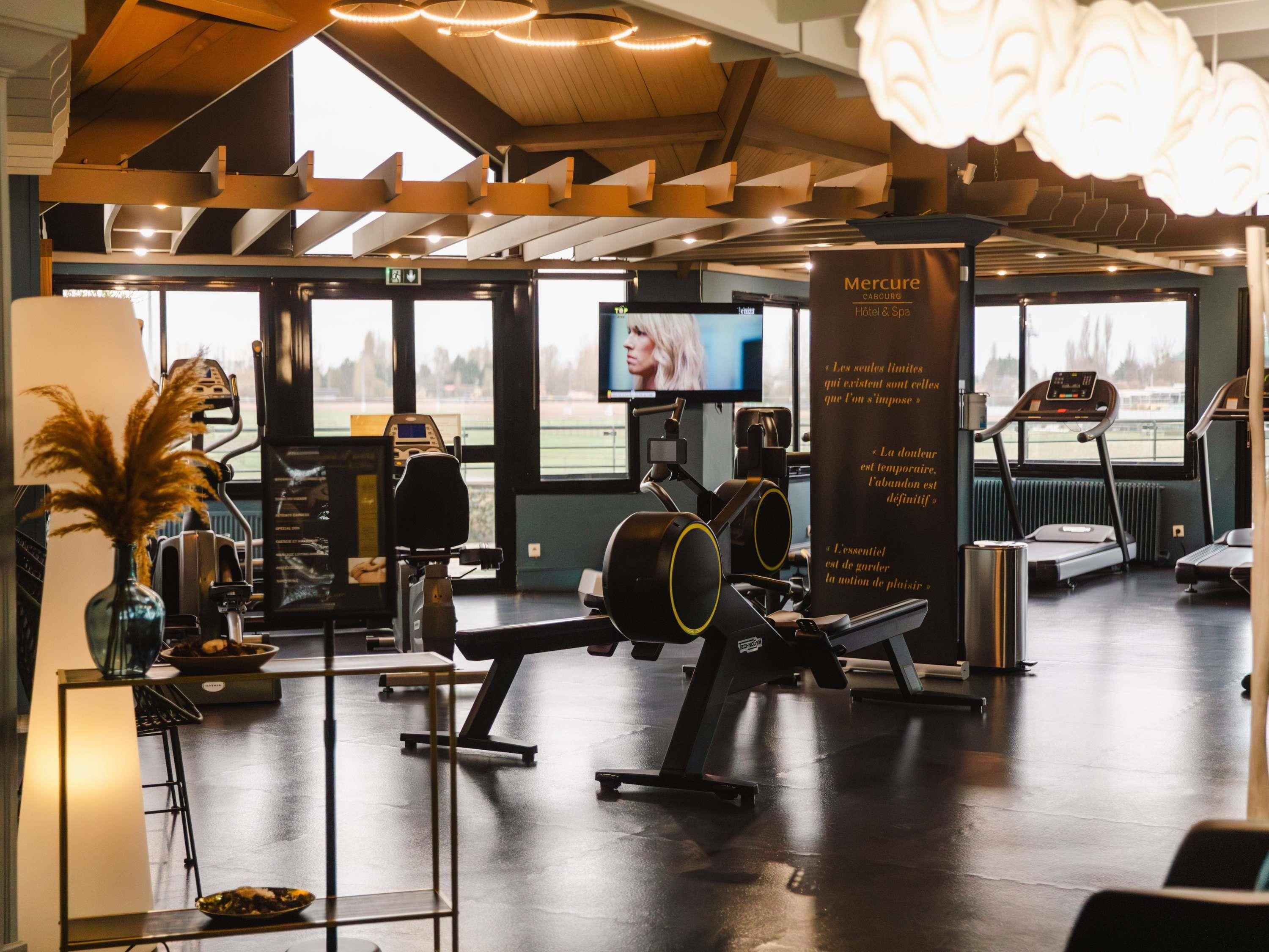 A gym with exercise equipment, a treadmill, and a large window with a view of a field.