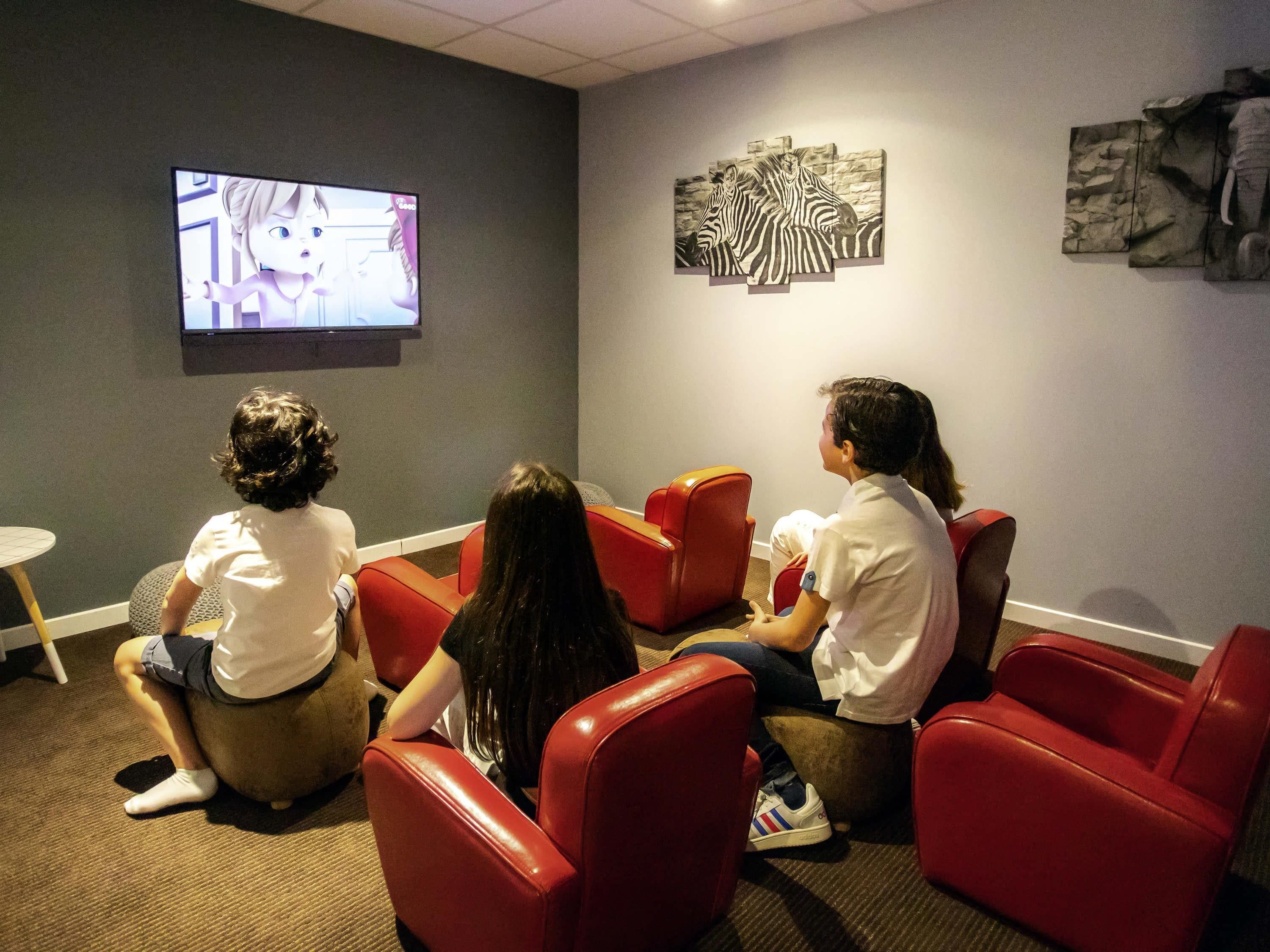 Habitación con asientos rojos, televisor y obras de arte en las paredes.