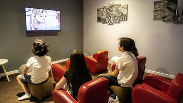 Habitación con asientos rojos, televisor y obras de arte en las paredes.