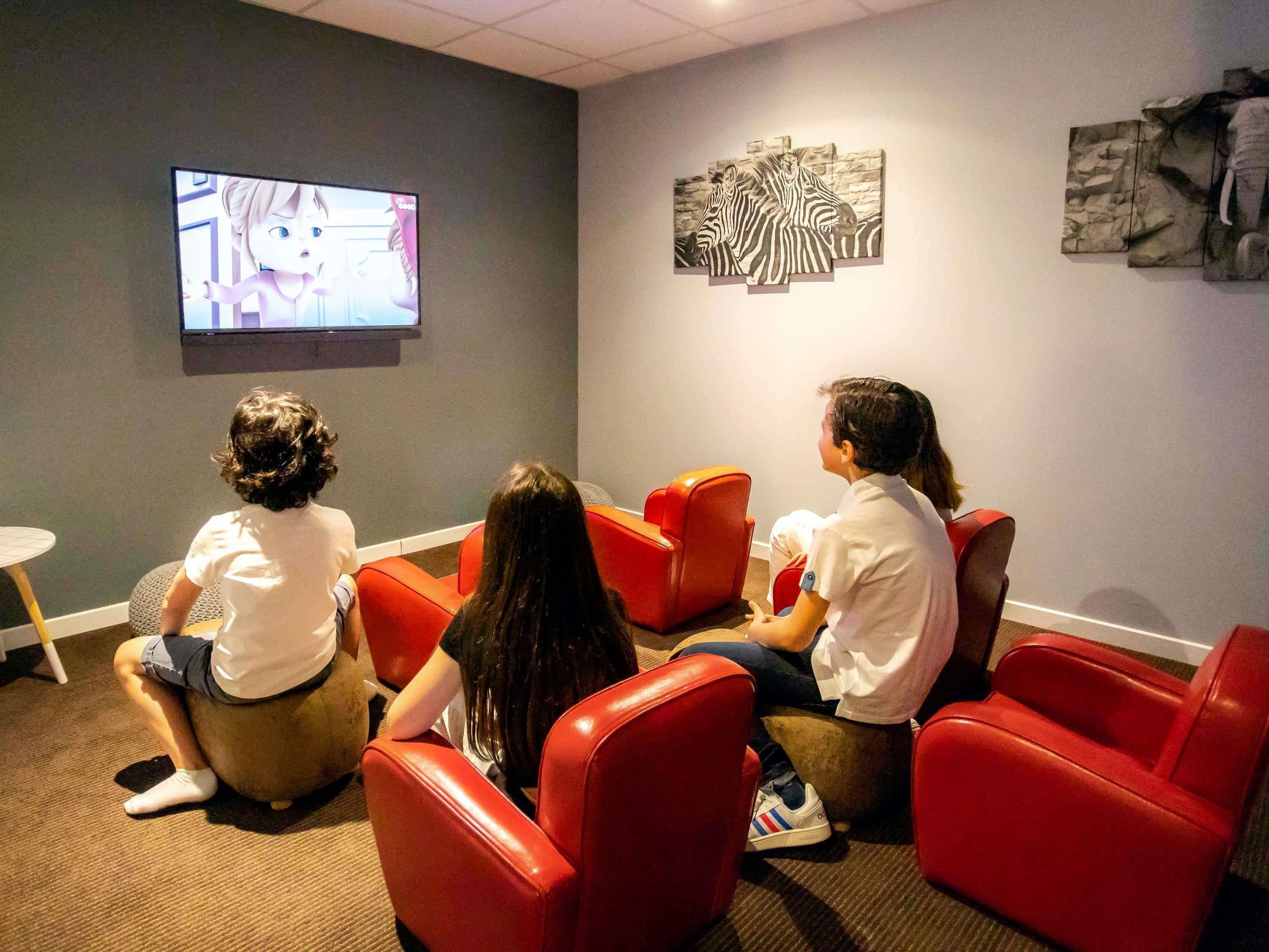 Habitación con asientos rojos, un televisor y decoración en la pared.