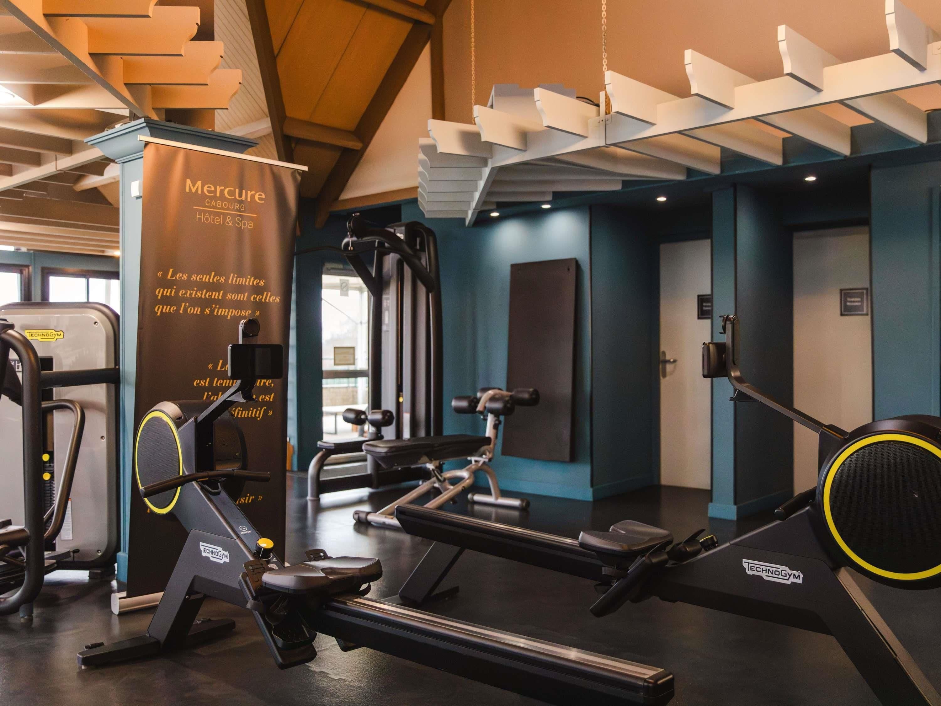 A gym with exercise equipment, a wall with motivational quotes, and a ceiling with unique light fixtures.