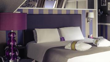 Una habitación de hotel con cama, escritorio, lámpara y estantería.