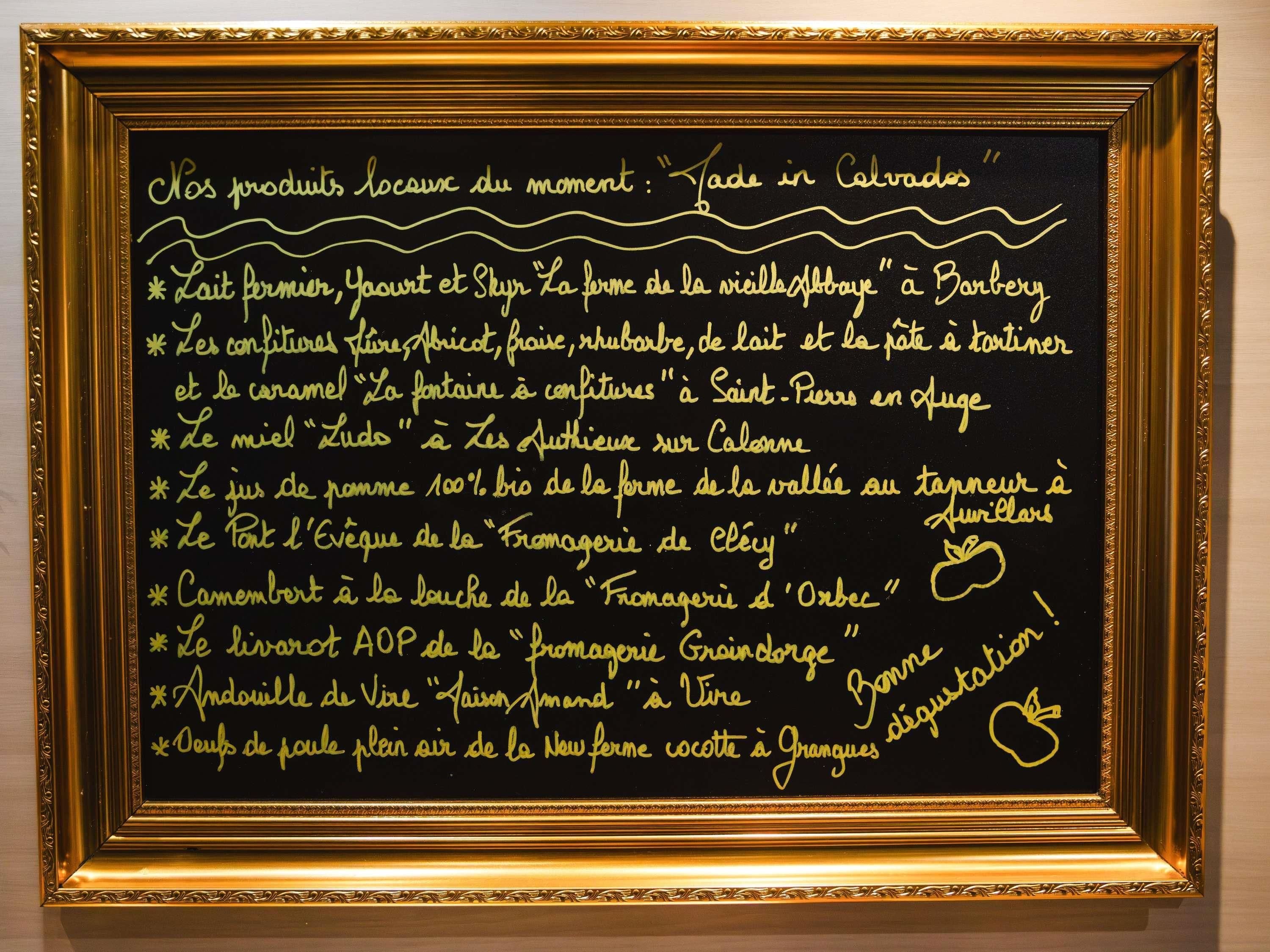 A framed blackboard with handwritten text listing local products and their origins.