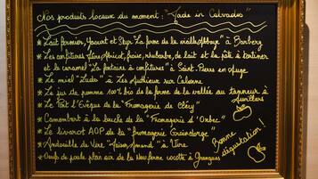 A framed blackboard with handwritten text listing local products and their origins.