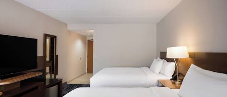 Habitación de hotel con dos camas, un televisor, una lámpara y una mesita de noche de madera.
