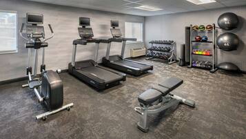 A gym with treadmills, a bench, dumbbells, and a rack of medicine balls.