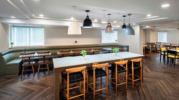 A modern dining area with a long table, multiple chairs, and pendant lighting.