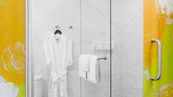 A modern bathroom with a glass-enclosed shower, a white toilet, and a robe hanging on a rack.