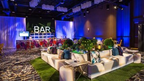 Un espace de détente moderne avec un bar, des canapés blancs et des touches de vert.