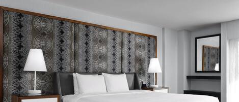 Una camera d'albergo moderna con un letto grande, due comodini e una testiera a motivi decorativi.