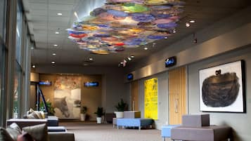 Una hall con un’installazione artistica a soffitto, zone relax e opere d’arte alle pareti.