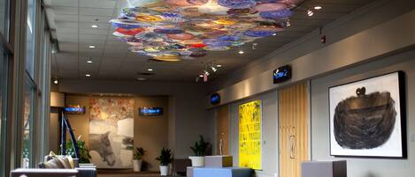 A lobby with a ceiling art installation, seating areas, and artwork on the walls.