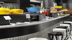 Un buffet proposant une variété de plats, un chat et un coin bar avec des tabourets.