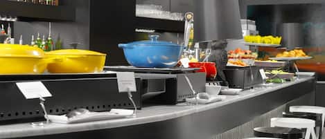 A buffet setup with various food items, a cat, and a bar area with stools.
