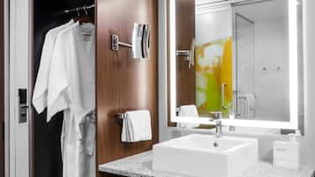 Une salle de bain moderne avec un grand miroir, un lavabo blanc et un meuble-lavabo en bois.