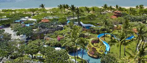 A resort with a pool area, palm trees, and a view of the ocean.