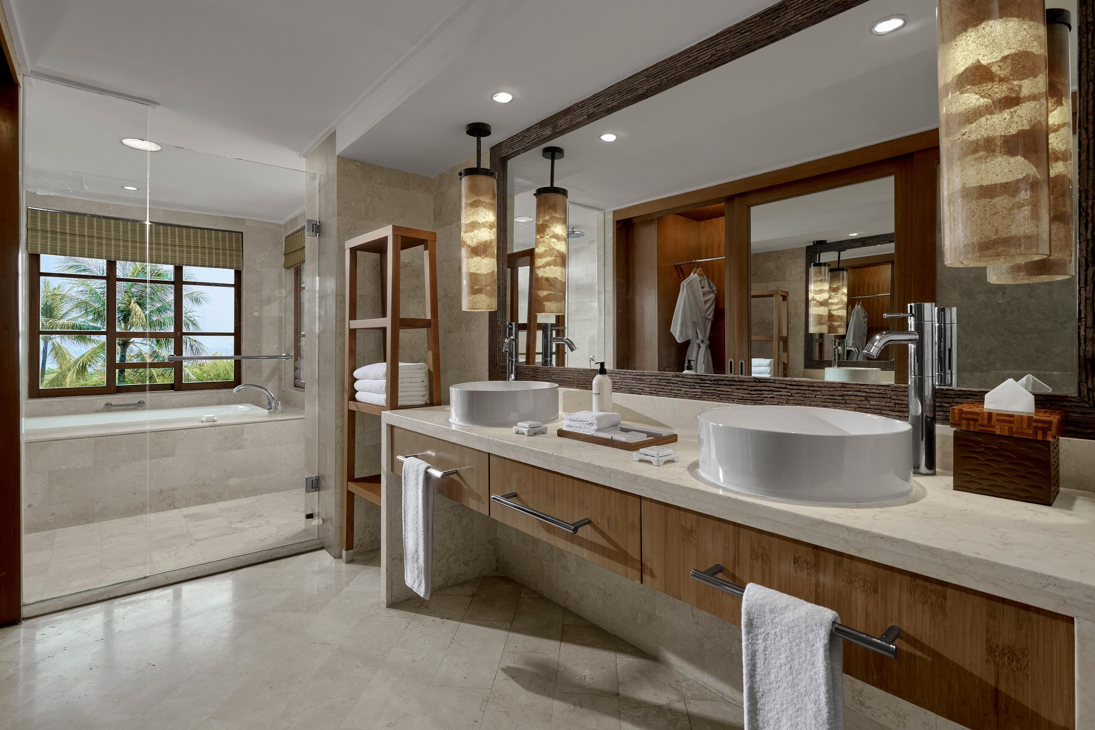 Un baño moderno con un espejo grande, dos lavamanos, una bañera y una ducha.