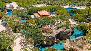 Un resort con piscina, palmeras y vista a la playa.