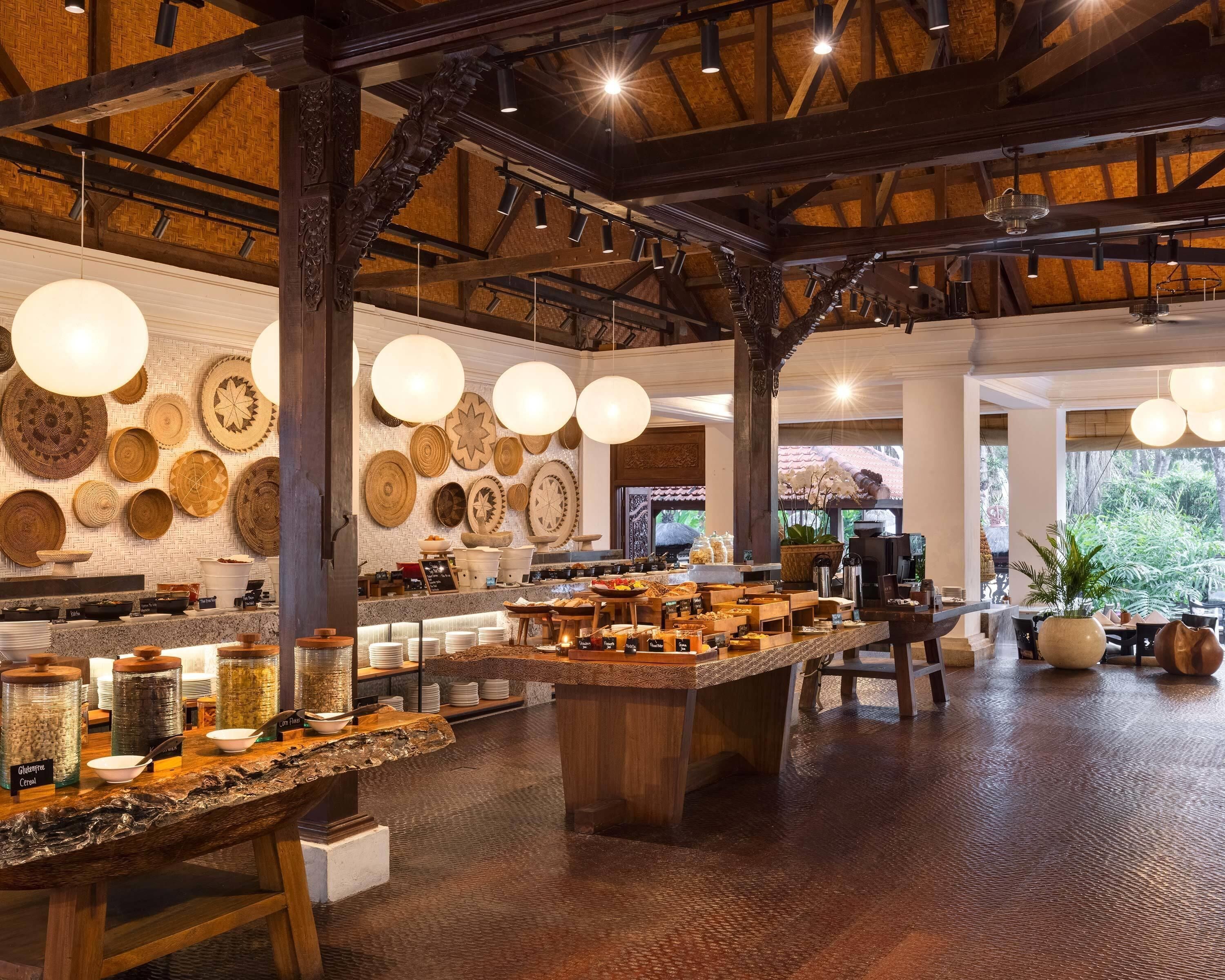 Un interior rústico con una larga barra que exhibe diversos alimentos y una pared decorada con platos tejidos.