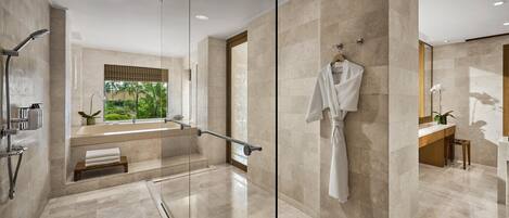 Un baño moderno con ducha de vidrio, bañera y ventana grande con vistas a la vegetación.