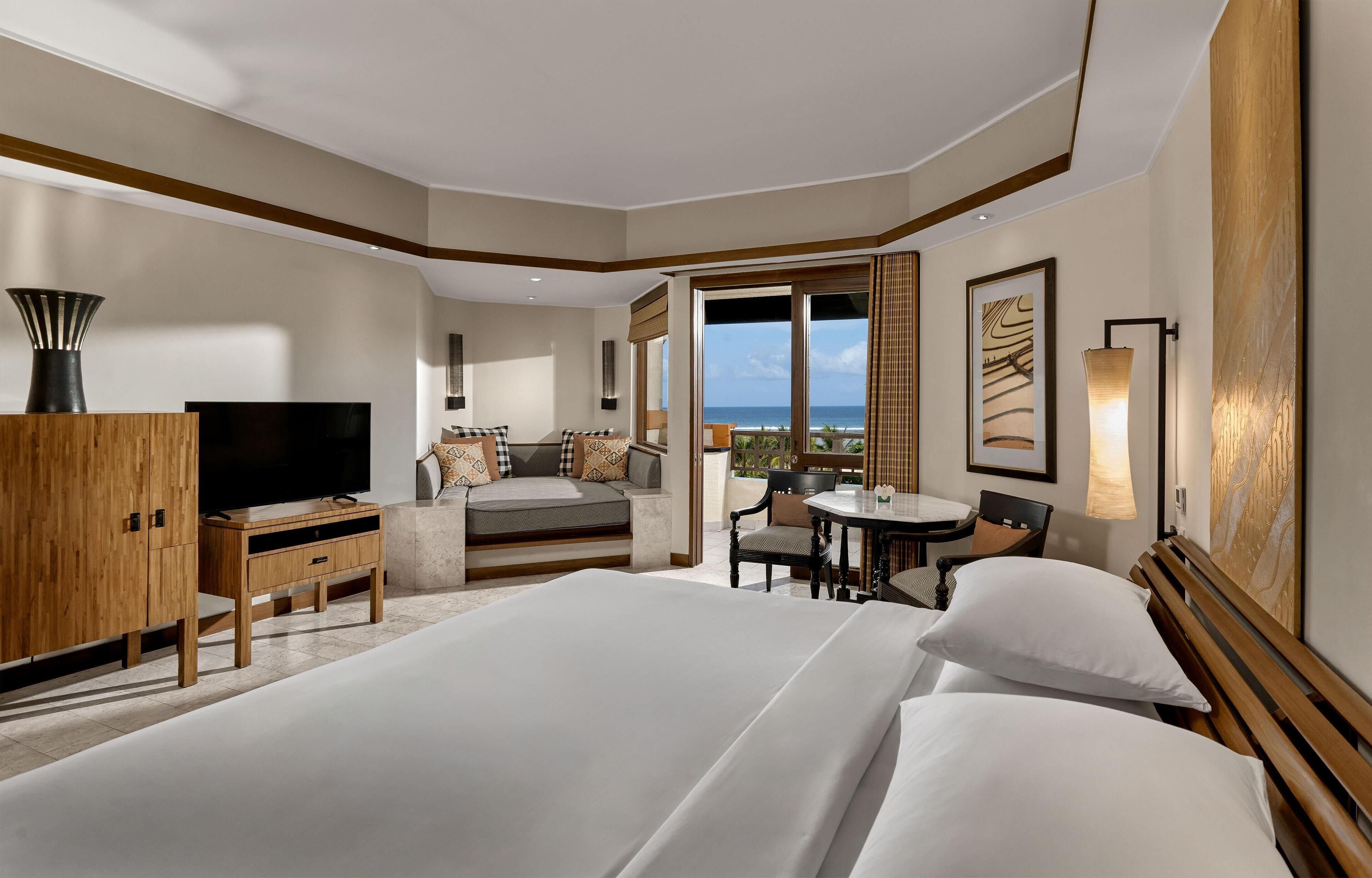 Una camera d'albergo con un letto grande, una scrivania con una sedia, una televisione e vista sull'oceano.