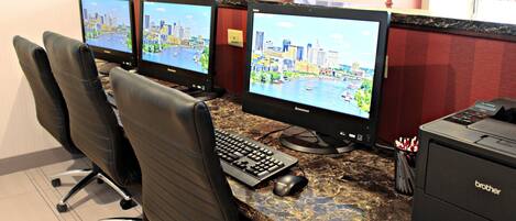 A reception desk with three computer monitors, a keyboard, a mouse, and a printer.