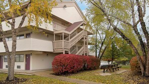A multi-story building with a balcony on the second floor, a covered outdoor area, and a picnic table. - Red Roof Inn PLUS+ Philadelphia Airport (Essington)